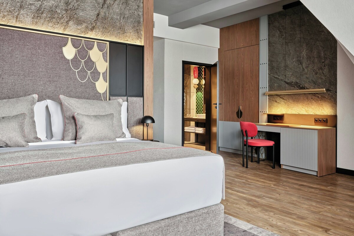 A modern bedroom with a bed, bedside table, and a desk area with a chair.