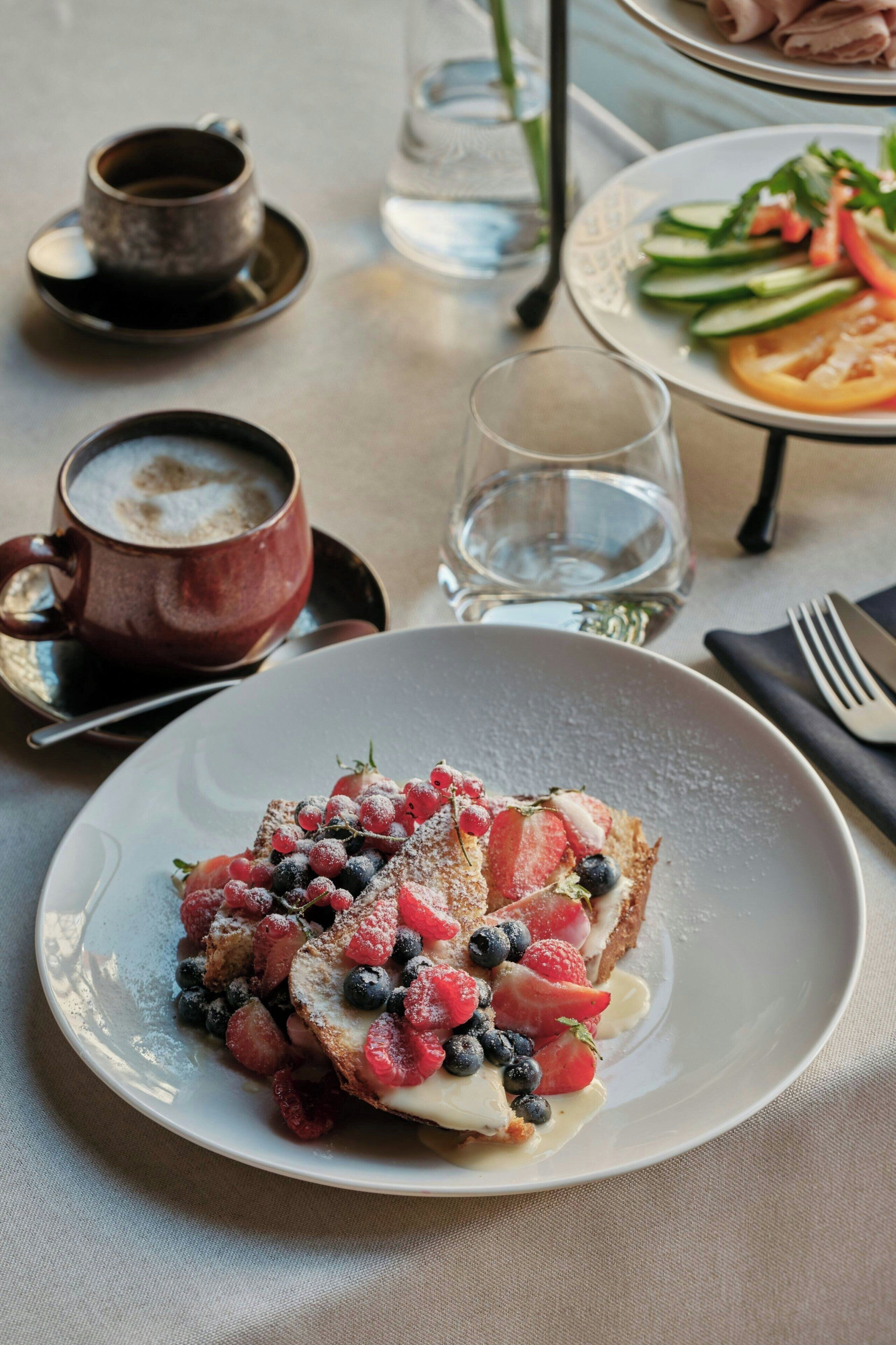 A dining table with a plate of food, a cup, and a glass.
