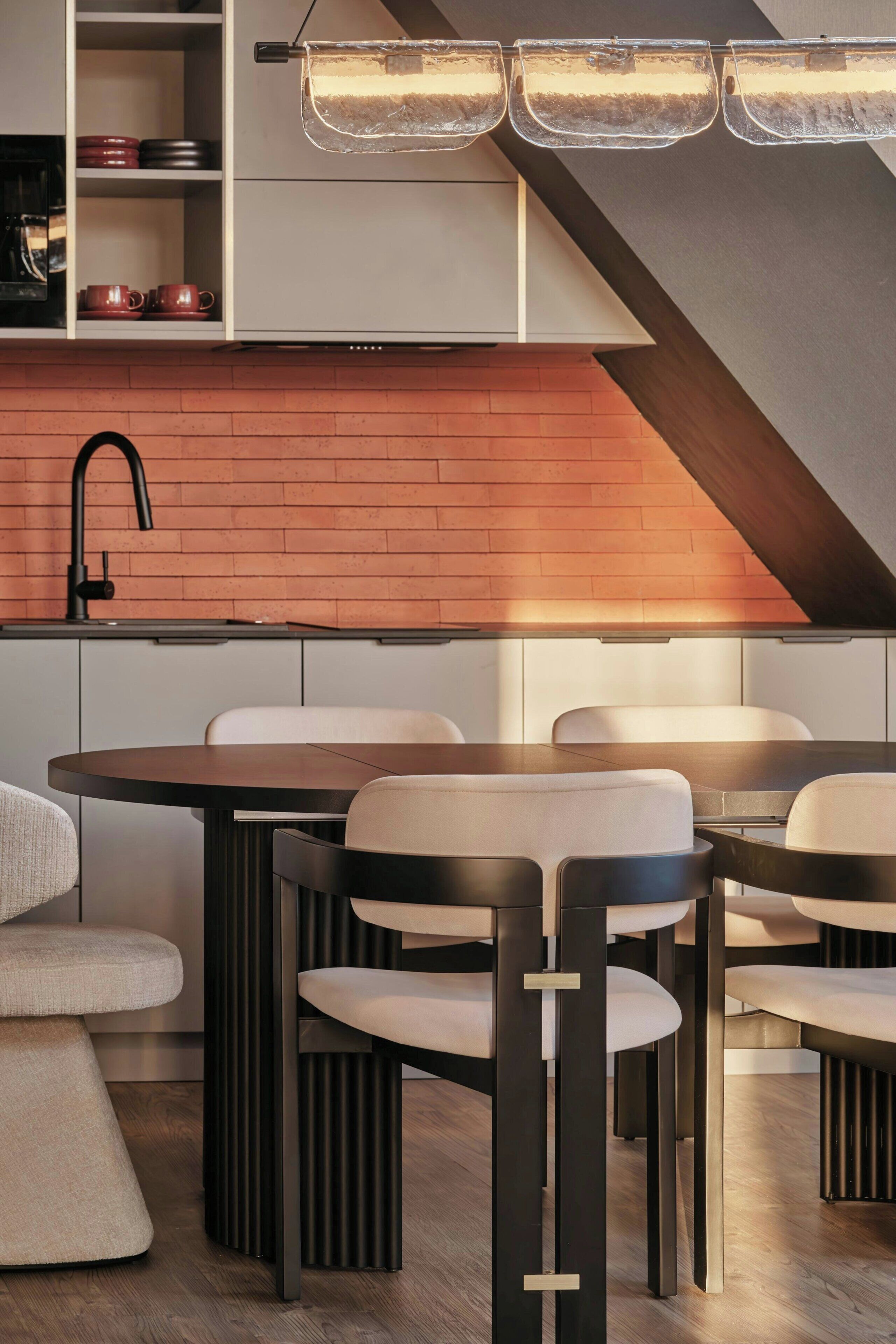 A modern kitchen with a brick backsplash, a black faucet, and a dining area with a round table and chairs.