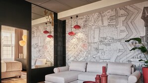 A modern living room with a sectional sofa, a coffee table, and a map wallpaper. - The Brick, a Tribute Portfolio Hotel - Adults Only (Gdansk)