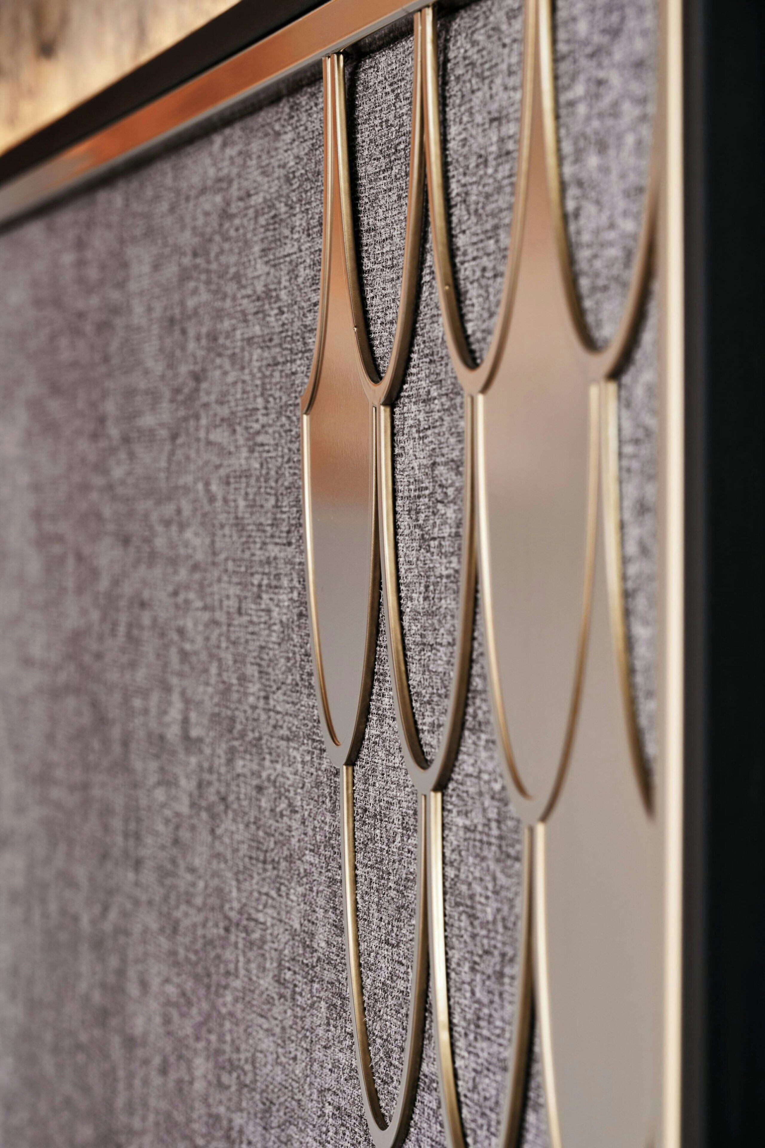 A close-up of a metallic, curved design element on a textured wall.