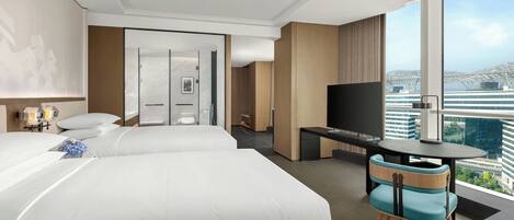 Una habitació d'hotel amb dos llits, un escriptori amb un televisor, una taula petita i una cadira.