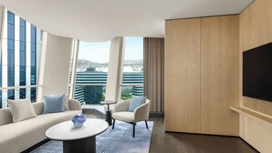 A modern hotel room with a sofa, chairs, a coffee table, a TV, and large windows offering a city view. - Marriott Shanghai Hotel Songjiang (Shanghai)