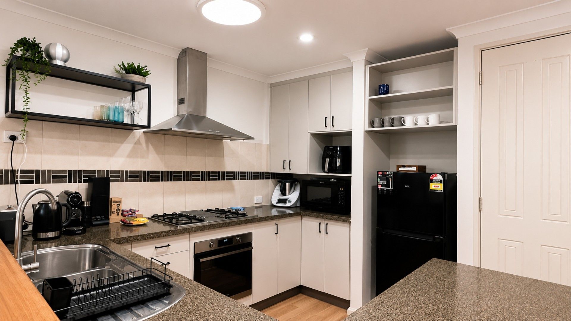 A modern kitchen with a gas stove, oven, microwave, and a black refrigerator.
