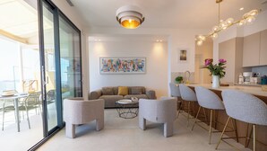 Ein stilvolles Wohnzimmer mit Sofa, Sesseln, einem Couchtisch und einer Bar mit Hockern.