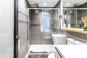 A modern bathroom with a glass-enclosed shower, a white sink, and a large mirror. - Modern Covent Garden Apartment (London)