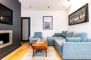 A modern living room with a grey sofa, a blue armchair, a wooden coffee table, and a framed picture on the wall. - Modern Covent Garden Apartment (London)