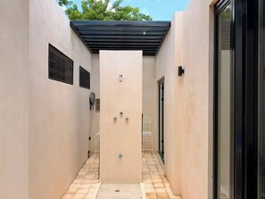 A narrow hallway with a central door, tiled floor, and a black-framed window on the left. - Ciricote House (Centro)
