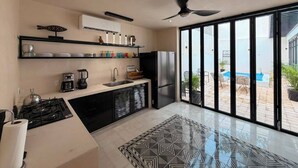 Eine moderne Küche mit Gasherd, Kühlschrank und einem großen Fenster mit Blick auf einen Swimmingpool.