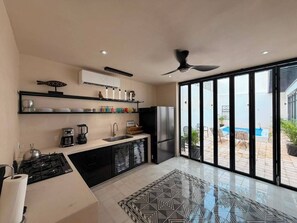 A modern kitchen with a gas stove, refrigerator, and a large window overlooking a swimming pool. - Ciricote House (Centro)