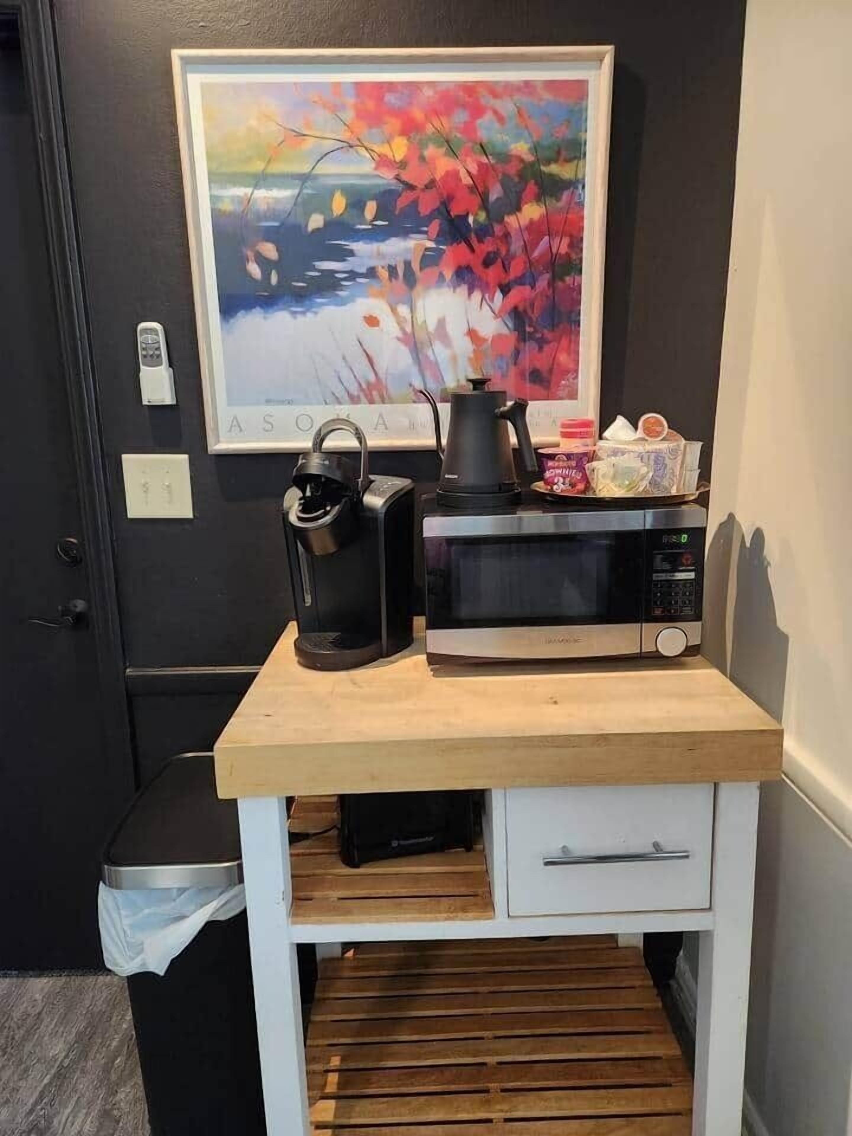 A kitchenette with a microwave, kettle, and a small cabinet.