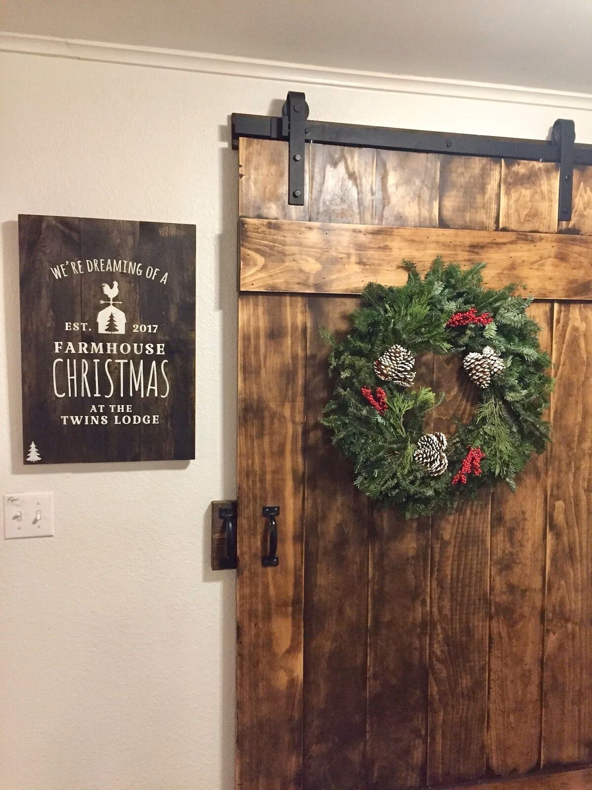 A rustic barn-style door with a decorative wreath and a sign above it.