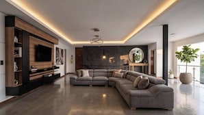 Una sala de estar moderna con un sofá seccional, unidad de entretenimiento empotrada y un gran ventanal que proporciona luz natural.