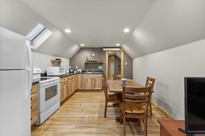 A kitchen with wooden cabinets, a white refrigerator, a microwave, and a dining table with chairs. - Black Hills Trailside Park Resort (Hill City)
