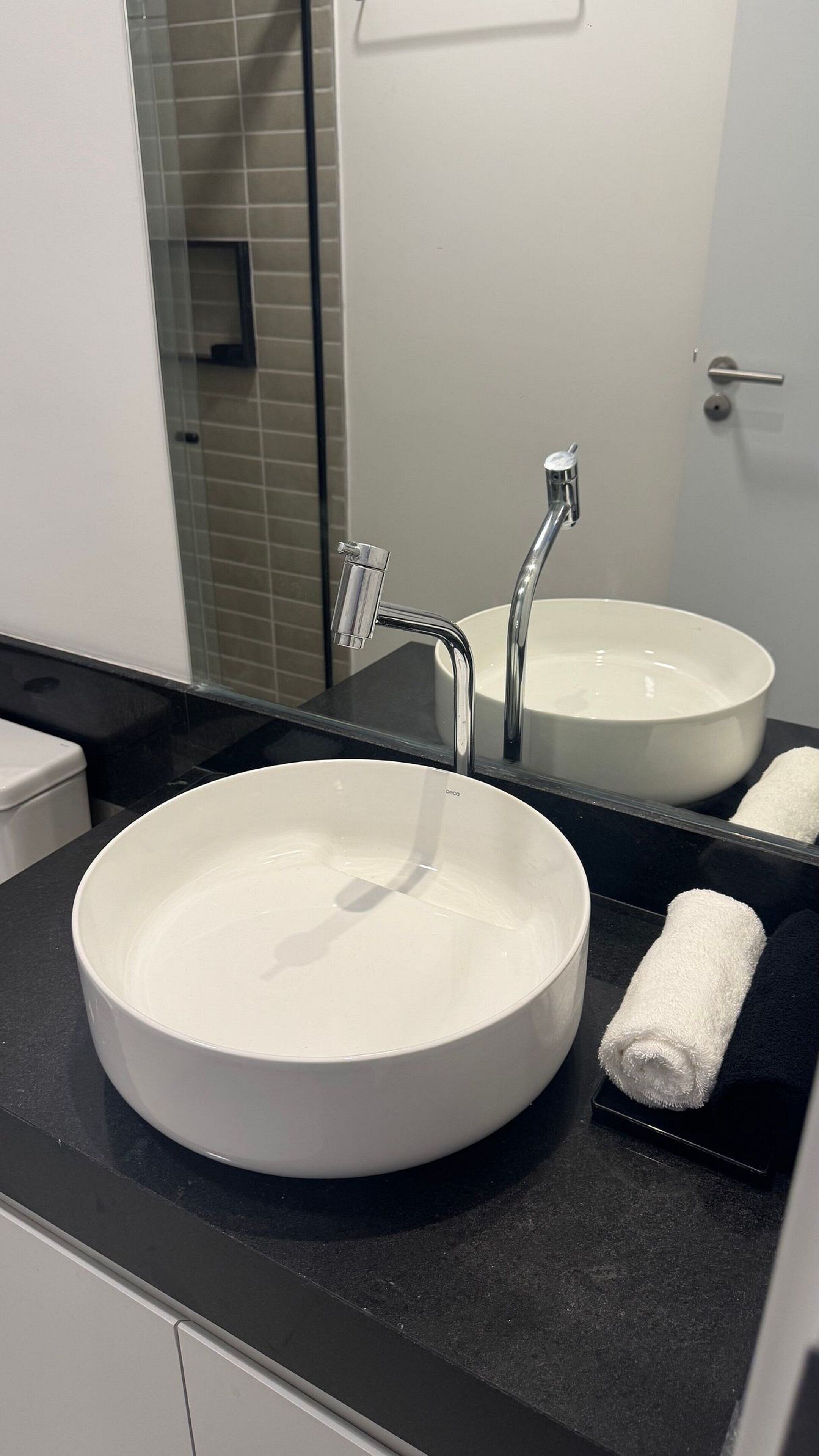 Un baño con un lavabo blanco redondo, un espejo y una toalla.