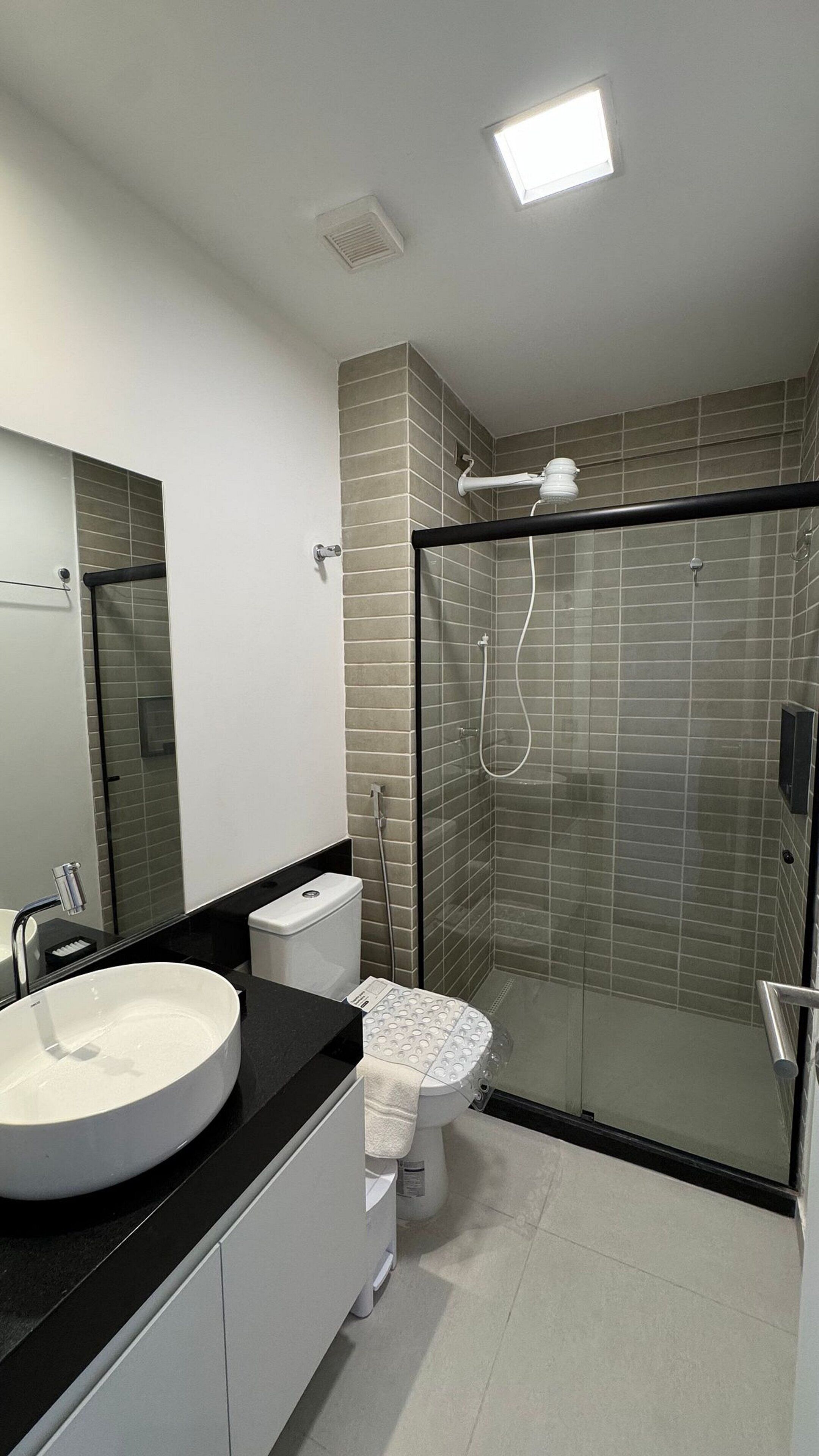 Een moderne badkamer met een glazen douchecabine, een wit toilet en een grote wastafel.