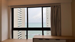 A room with a large window overlooking a body of water and high-rise buildings.