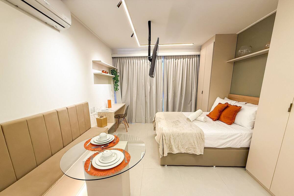 Una habitación de hotel moderna con cama, un pequeño rincón de descanso con mesa, y un escritorio.