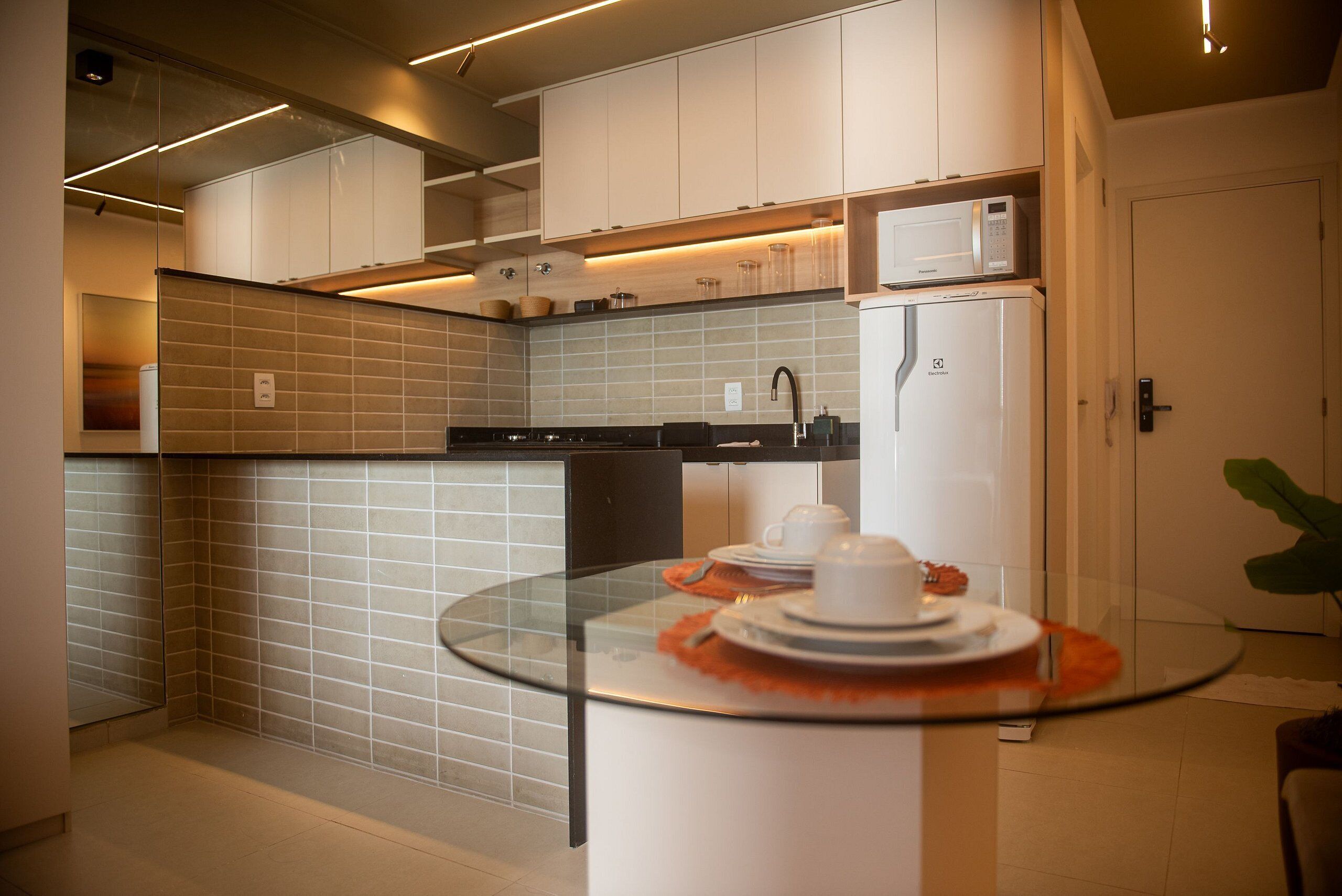 A modern kitchen with white cabinets, a microwave, and a refrigerator.