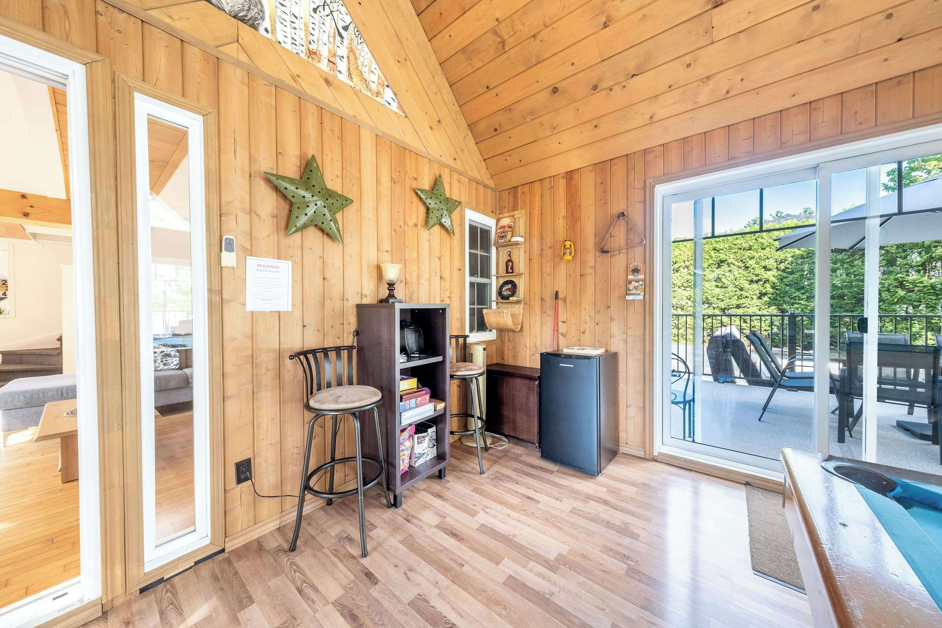 Un intérieur en bois comprenant une piscine, des tabourets de bar, une bibliothèque et un réfrigérateur.