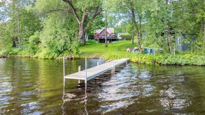A riverside property with a dock, a red house, and surrounding greenery.