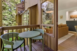 A wooden deck with two chairs and a table, a sofa, and a painting on the wall.