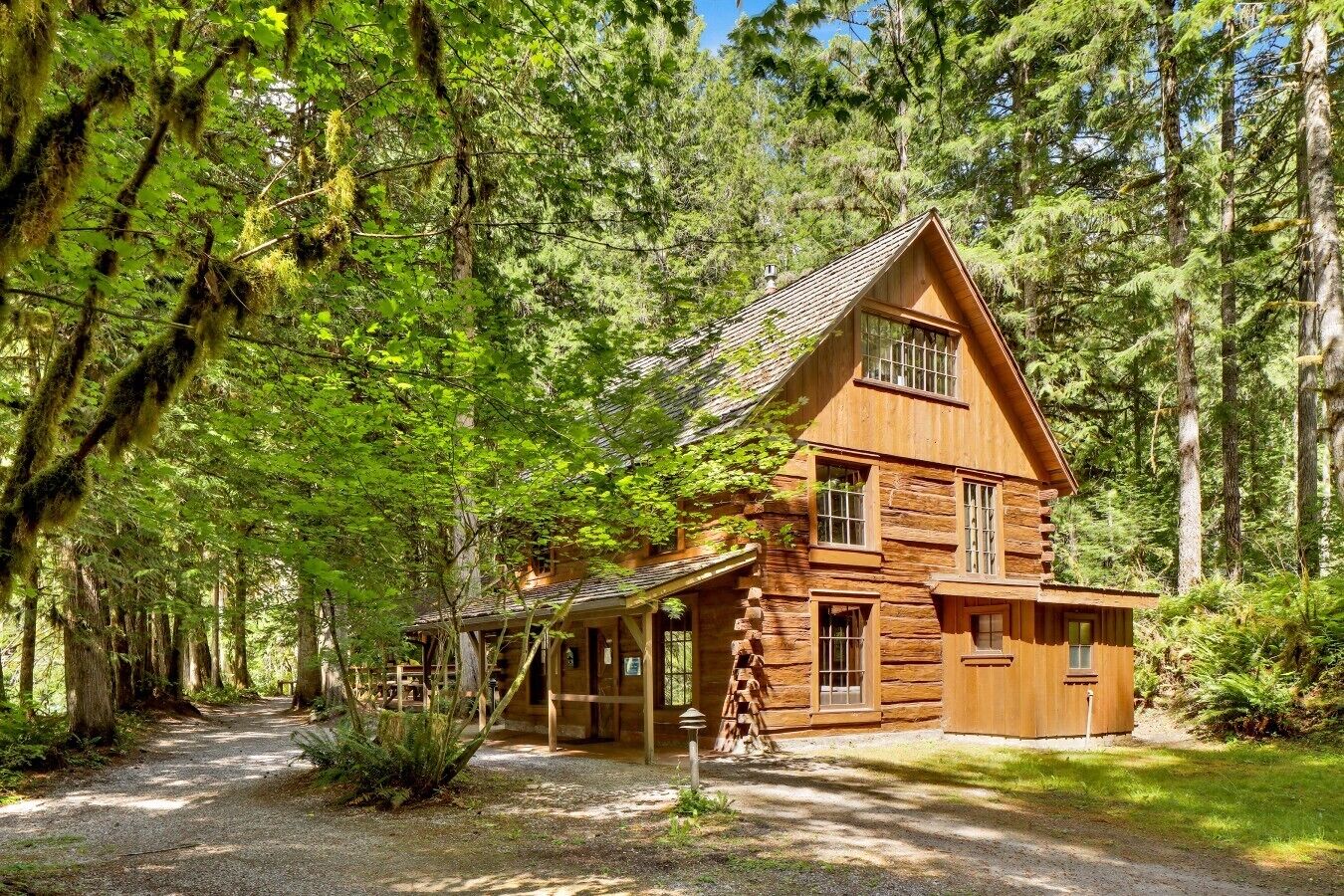 Une cabane en rondins avec un toit à forte pente, de nombreuses fenêtres et une véranda.