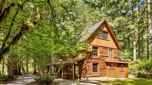 A log cabin with a steeply pitched roof, multiple windows, and a porch.
