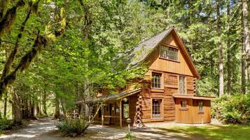 Une cabane en rondins avec un toit à forte pente, de nombreuses fenêtres et une véranda.