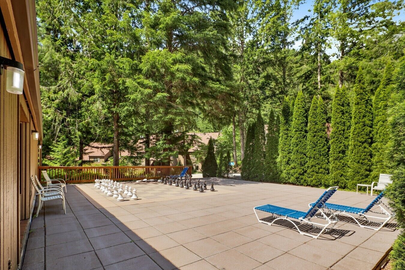 A covered outdoor area with lounge chairs, a pool table, and a wooden deck.