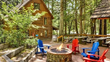 Une cabane en rondins avec un foyer en pierre et des fauteuils Adirondack.