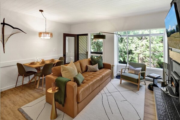 A modern living room with a sofa, a dining table, and a fireplace.