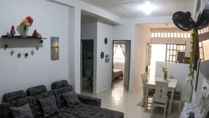 Una sala de estar con un sofá, una mesa de comedor con sillas y un pasillo que conduce a otra habitación.