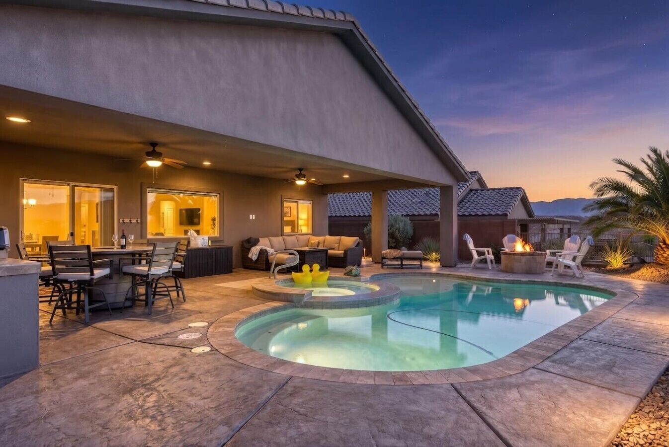 Un patio trasero con piscina, mobiliario de exterior y una chimenea.
