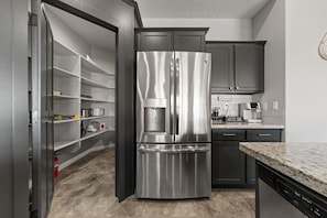A kitchen with a stainless steel refrigerator, dark cabinets, and a granite countertop. - Mountain Vista Hideaway by J and Amy BL 992768 (Mesquite)