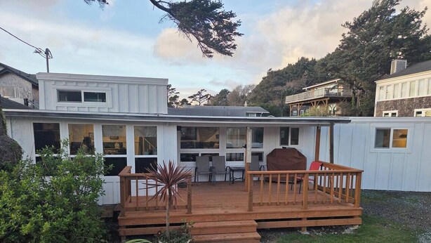 A single-story house with a deck, a small garden, and a clear sky. - Arch Cape cottage with a View (Arch Cape)