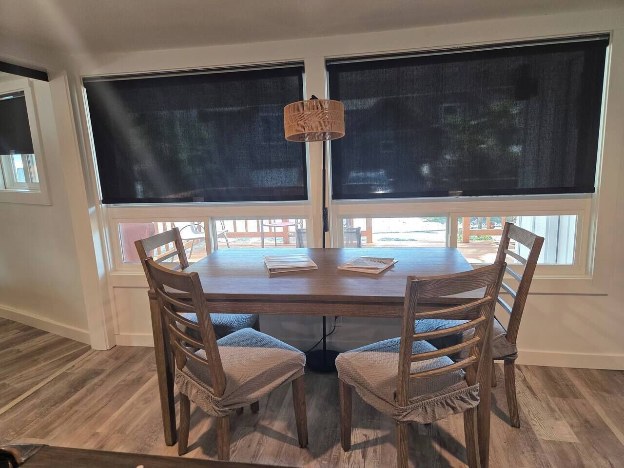A dining area with a round table, four chairs, and large windows.