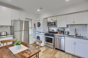 Cozinha compacta com geladeira, micro-ondas, fogão, forno e máquina de lavar.