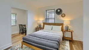 A bedroom with a bed, two bedside tables with lamps, a headboard, a window with blinds, and a chair. - Dormont, Potomac @3 Stylish and Cozy 2 Bedroom Private Apartment (Pittsburgh)
