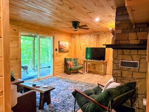 A wooden interior with a television, a sofa, and a chair.