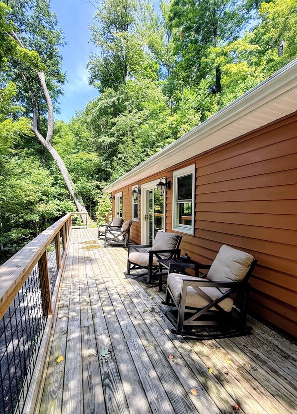 A wooden deck with outdoor seating and a view of a forested area.