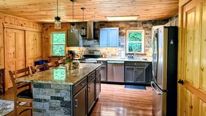 A kitchen with wooden cabinets, a stone island, and a built-in oven. - Modern 4-bedroom cabin close to Liberty Mountain (Fairfield)