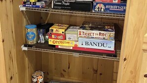 A wooden shelf with board games and a tin of JERSEY chips.