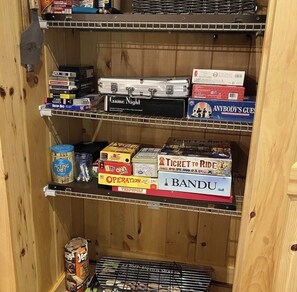 Un estante de madera con juegos de mesa y una lata de papas JERSEY.