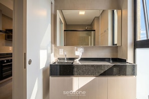A modern bathroom with a large mirror, a sink, and a shower. - Studio in Condo w/ Gym in Trindade Vtd0610 (Florianópolis)