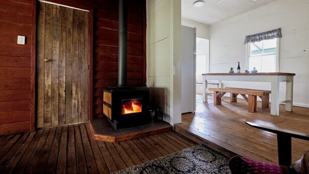 Un interior de madera con chimenea, un banco y una mesa.