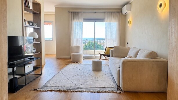 Ein Wohnzimmer mit Sofa, Sesseln, Fernseher und Bücherregal.