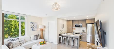 A modern kitchen with a central island, stainless steel appliances, and a dining area with bar stools.