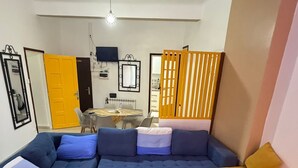 A living room with a sectional sofa, a small table, a TV, and a patterned rug.