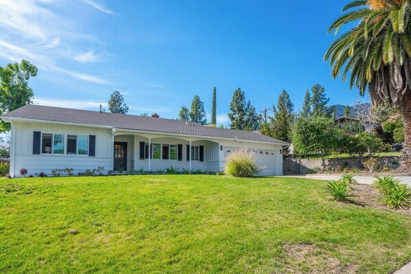 A single-story house with a covered porch, a garage, and a well-maintained lawn.